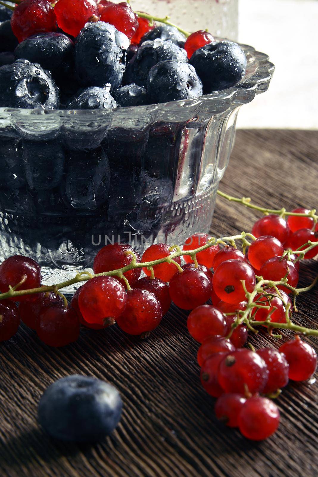 Blueberries and currants in a vase. Water drops