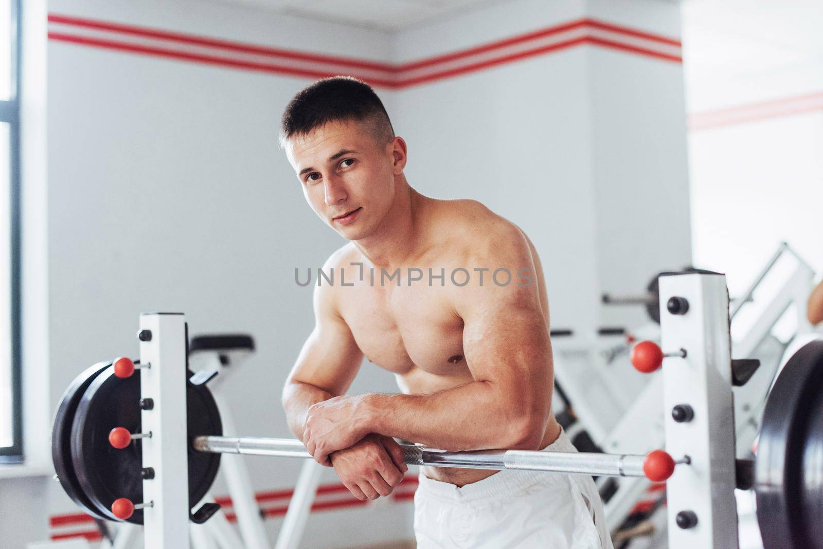 Beautiful man with big muscles, posing for the camera in a nice bright room gym. Sport. Fitness