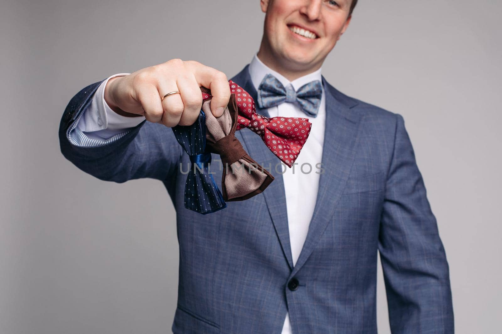 Smiling man insmart suit keeping bow ties in hand by StudioLucky