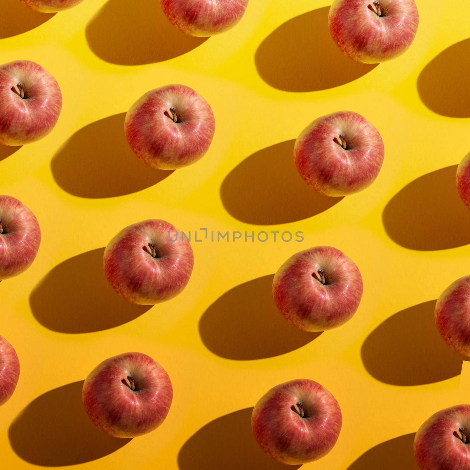 Red apples with shadows pattern on a yellow background