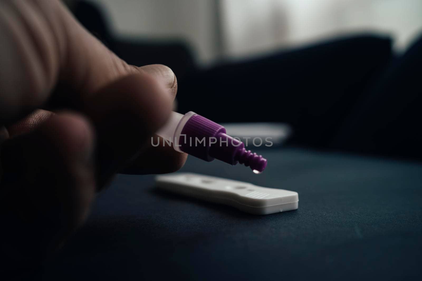 closeup of a young caucasian man, at home, places his own sample in the covid-19 antigen diagnostic test device by barcielaphoto