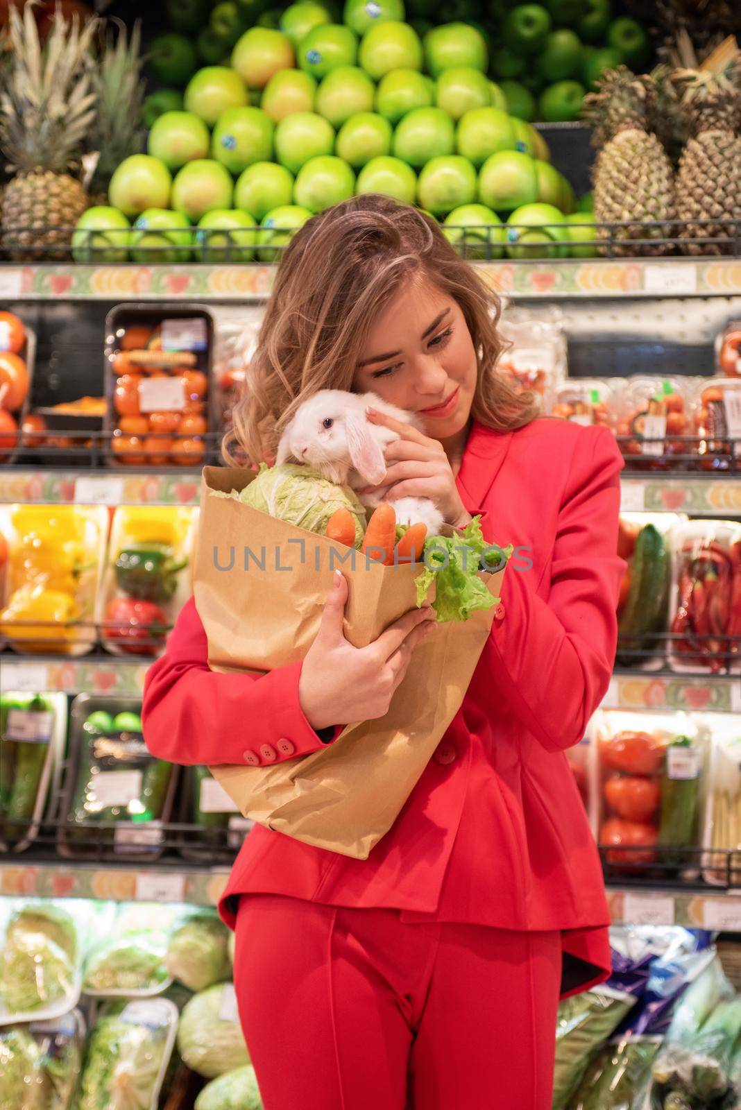 The young pretty woman is shopping to buy vegetables for her pet white rabbit at the supermarket