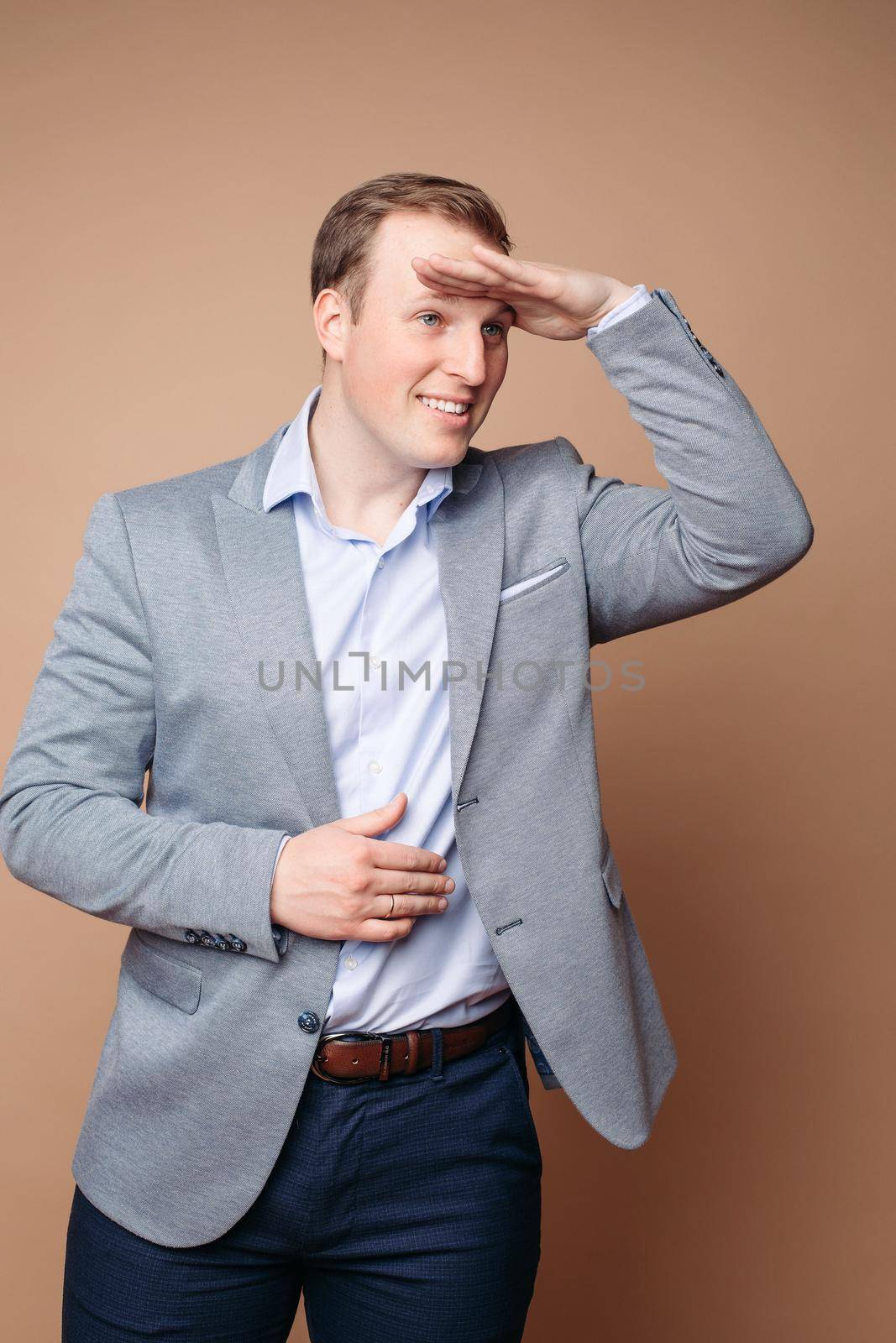 Charming caucasian male with short chestnut hair looks into the distance, picture isolated on peach background