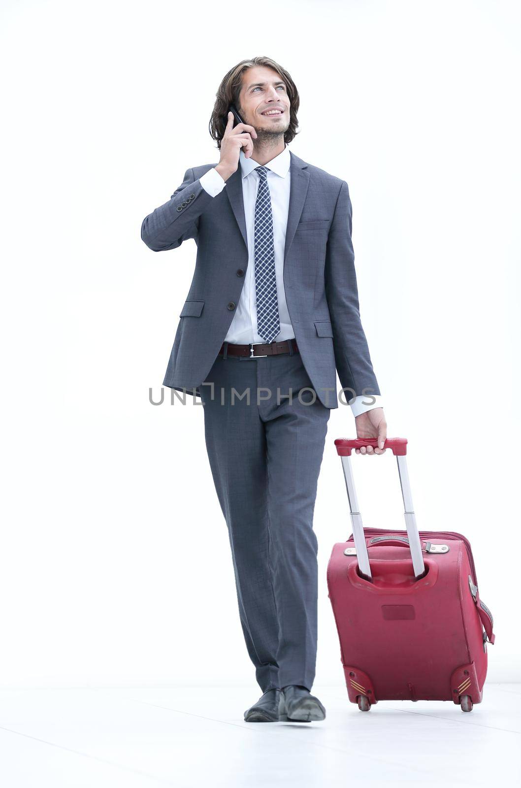closeup.a successful businessman with travel suitcase talking on the phone.