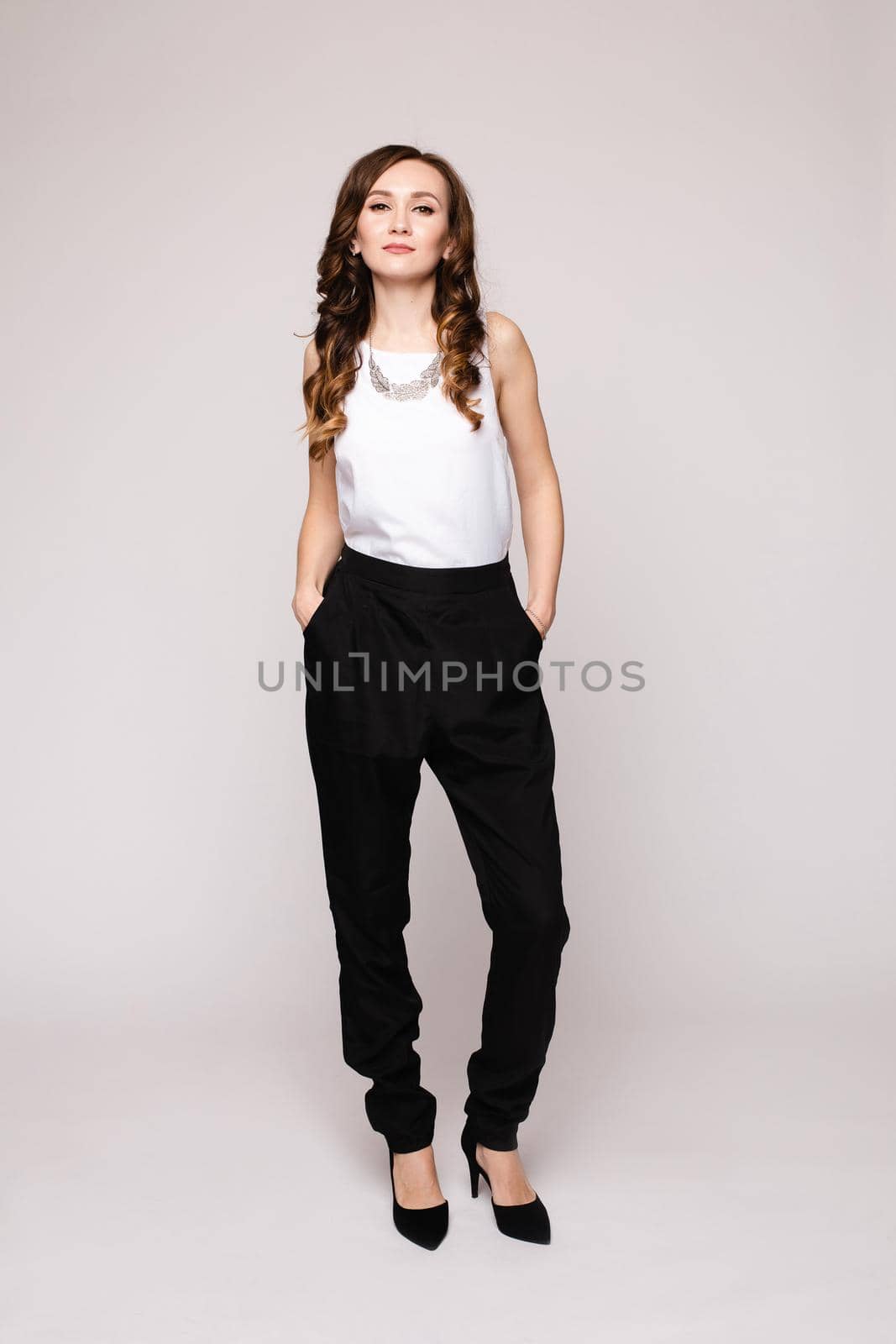 Front view of elegant successful female wearing smart outfit and glasses and posing on isolated background. Intelligent woman with folded arms looking at camera in studio. Concept of job and business.