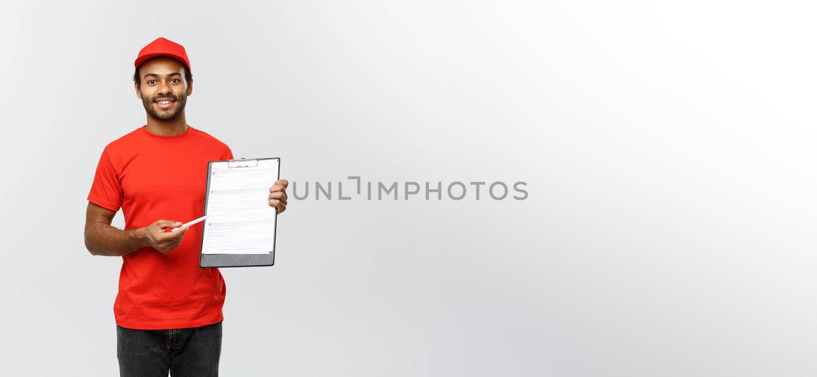 Delivery Concept - Portrait of Handsome African American delivery man or courier showing a confirmation document form to sign. Isolated on Grey studio Background. Copy Space