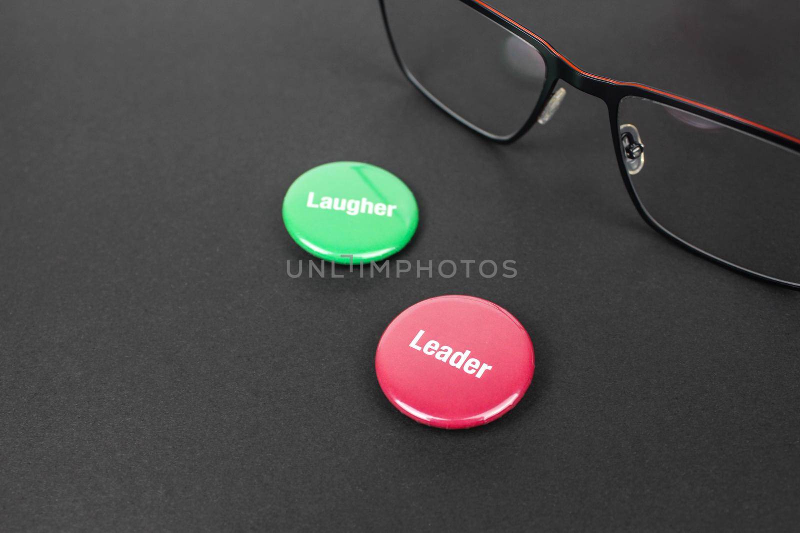 Colored plastic magnetic buttons on a black background next to glasses.