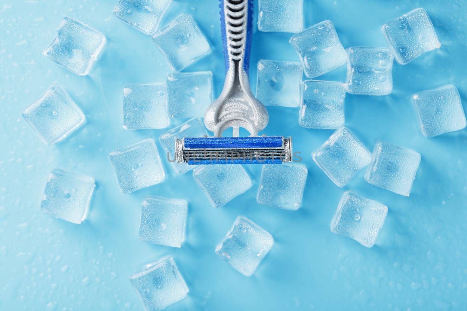 Shaving machine on a blue background with ice cubes. The concept of cleanliness and frosty freshness