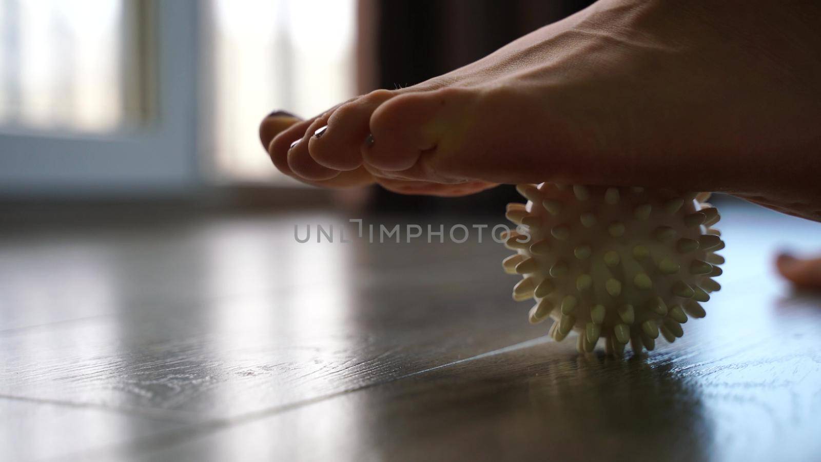 Close-up, a woman doing a foot massage with a special massage ball. The concept of prevention and treatment of flat feet