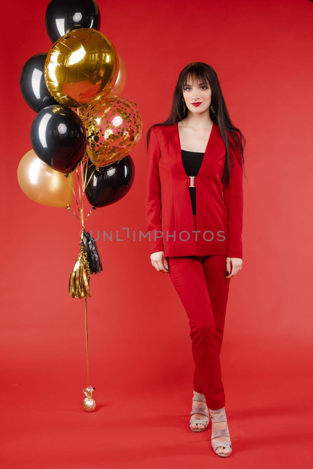 Young brunette model in red costume posing near balloons. by StudioLucky