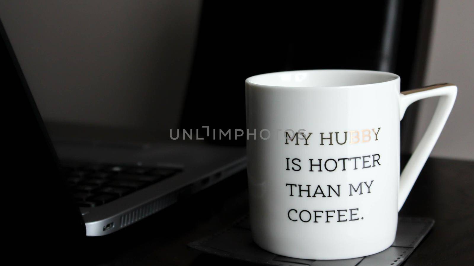 White cup with inspirational words standing next to laptop on wooden table indoors by JuliaDorian