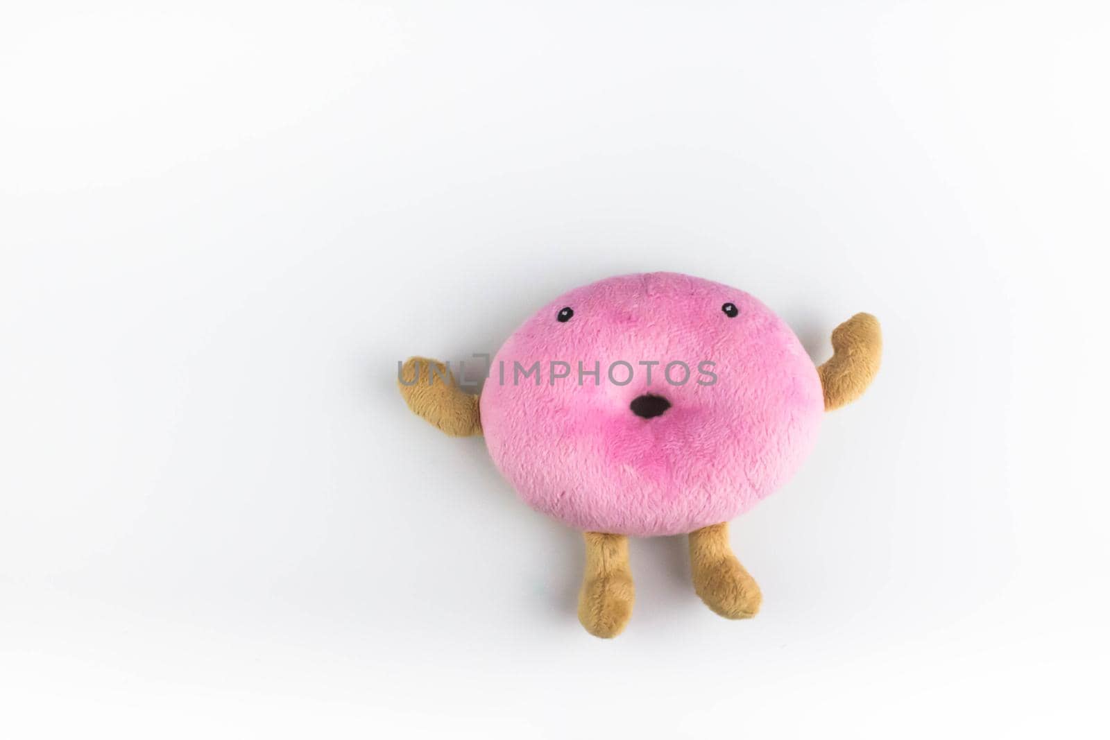 Top view of pink funny plush donut toy on isolated white background.