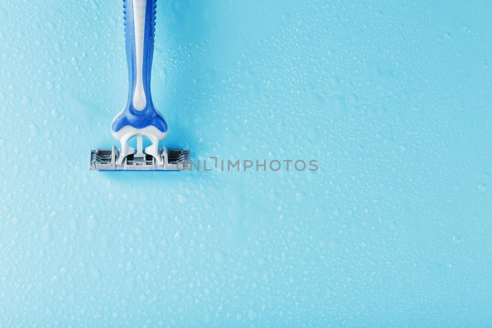 Razor blades on a blue background with drops of icy water close-up free space. The concept of purity and freshness