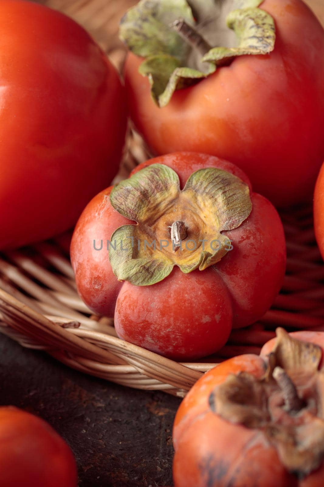 Different fresh persimmons on a dark background