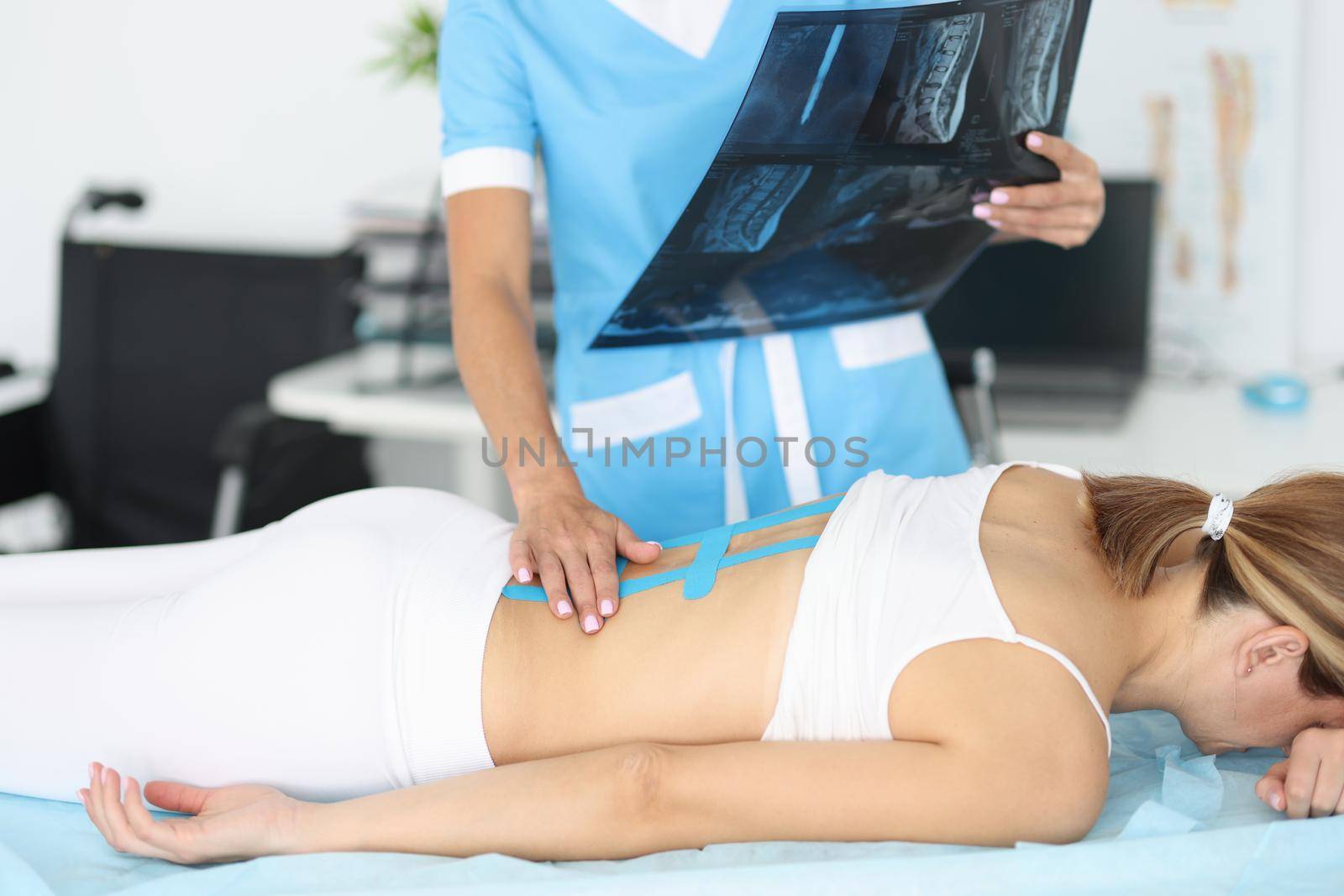 Close-up of doctor examine x ray scan, woman with back damage, massaging hurting spots. Treatment for faster recovery. Rehabilitation room, health concept