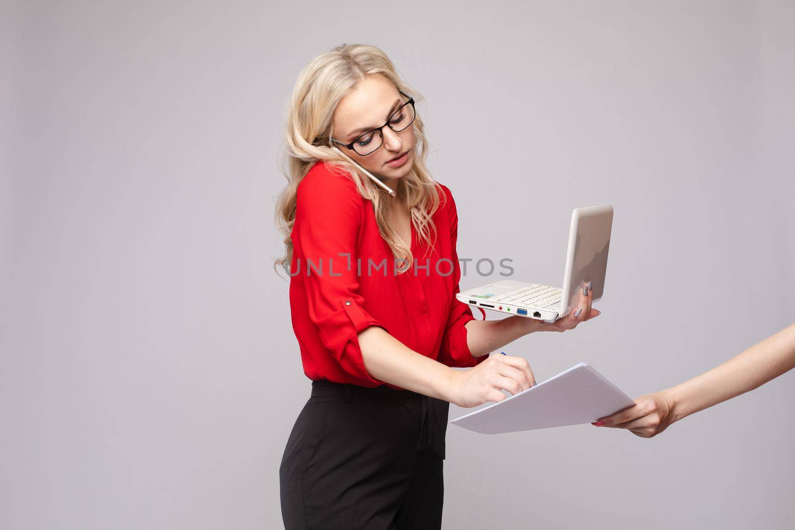 Woman talking by phone, using computer and signing papers by StudioLucky