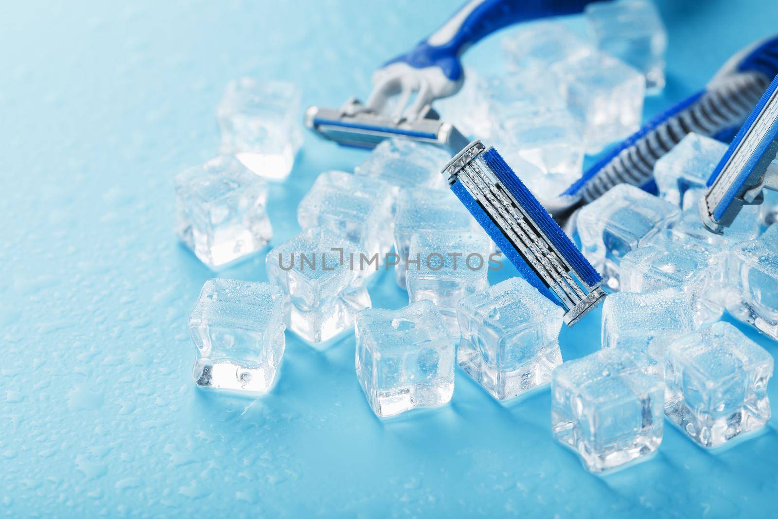 Shaving machine on a blue background with ice cubes. The concept of cleanliness and frosty freshness