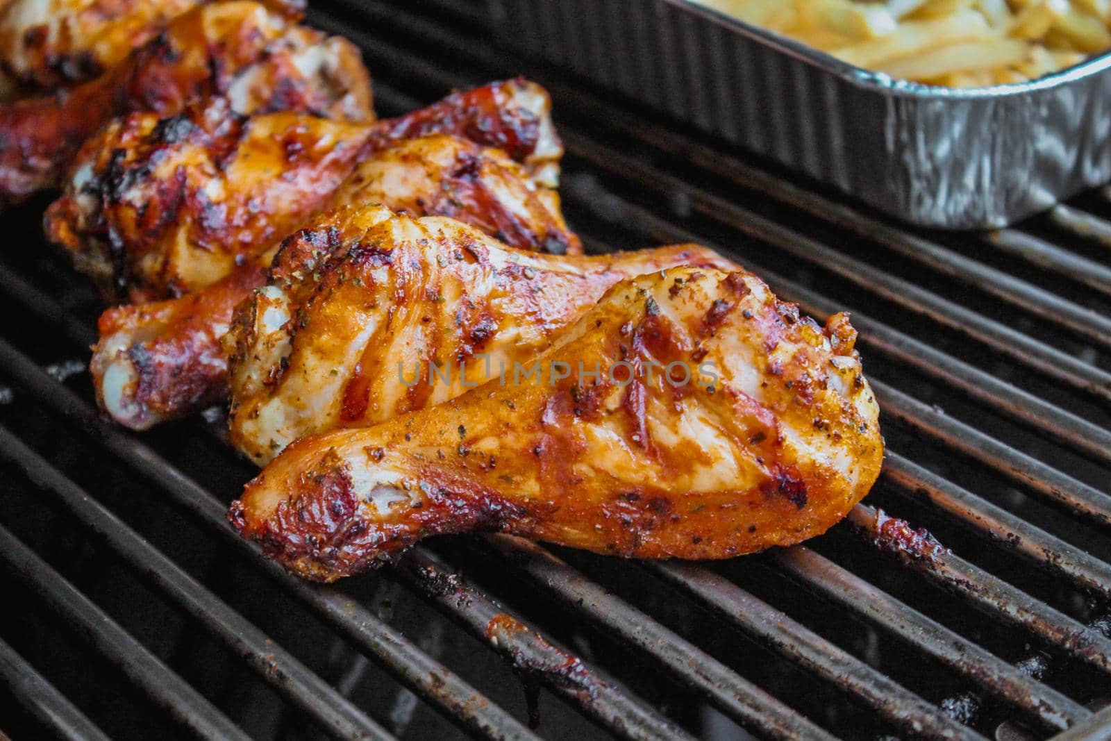 Grilled chicken on barbeque grill macro, delicious meat cooked on wooden charcoals with smoke