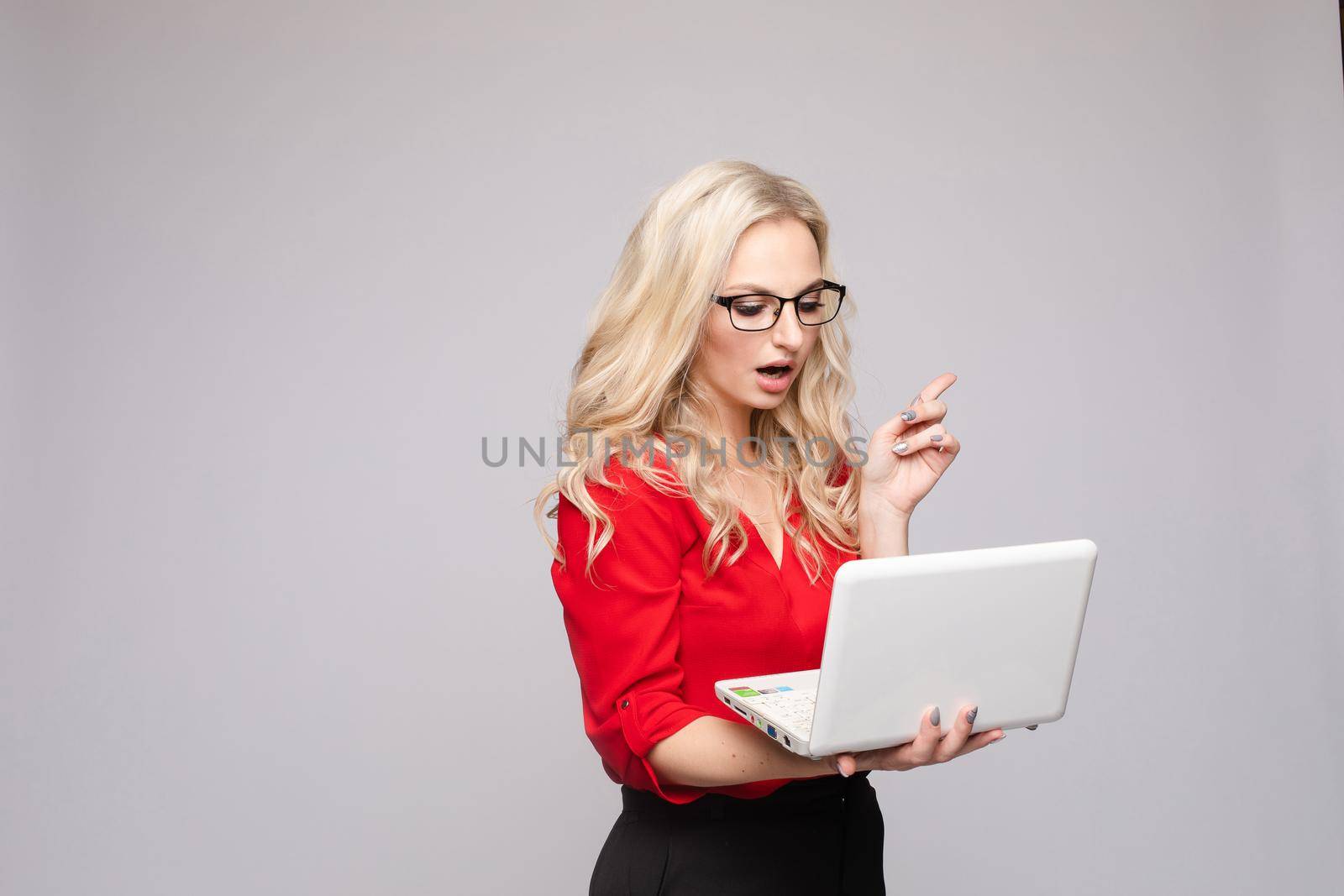 Shocked woman with open mouth keeping computer by StudioLucky