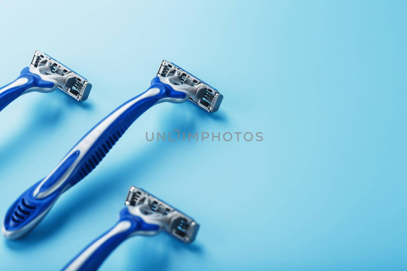 Blue shaving machine with sharp blades on the background of ice cubes close-up. The concept of cleanliness and frosty freshness