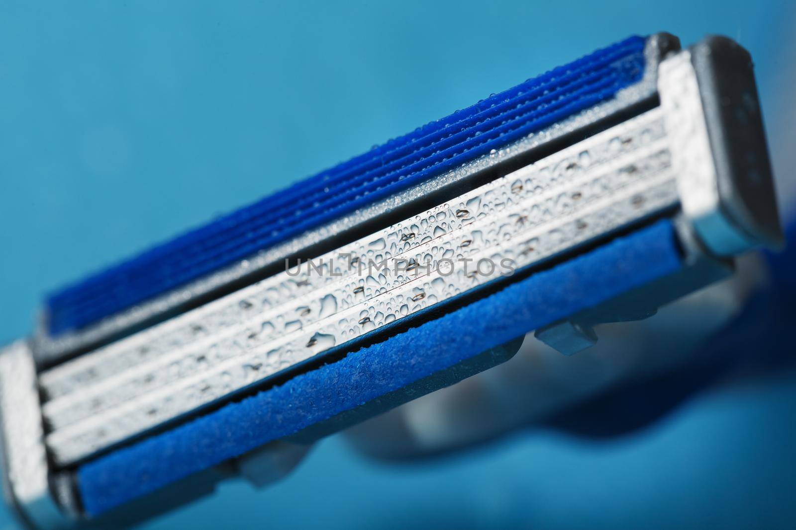 Razor blades on a blue background with drops of icy water close-up free space. The concept of purity and freshness
