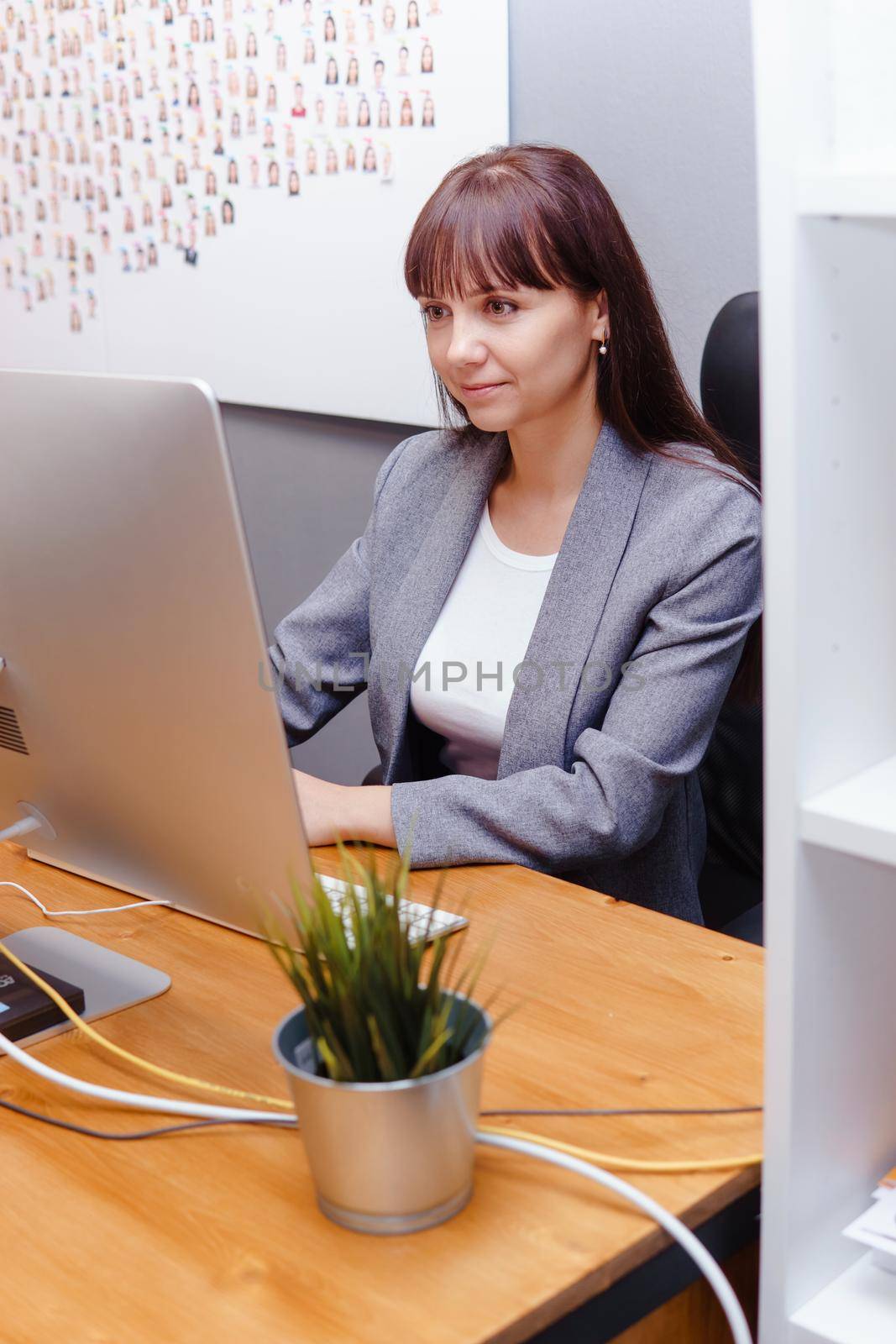 A brunette woman at a computer in the workplace. Business concept.