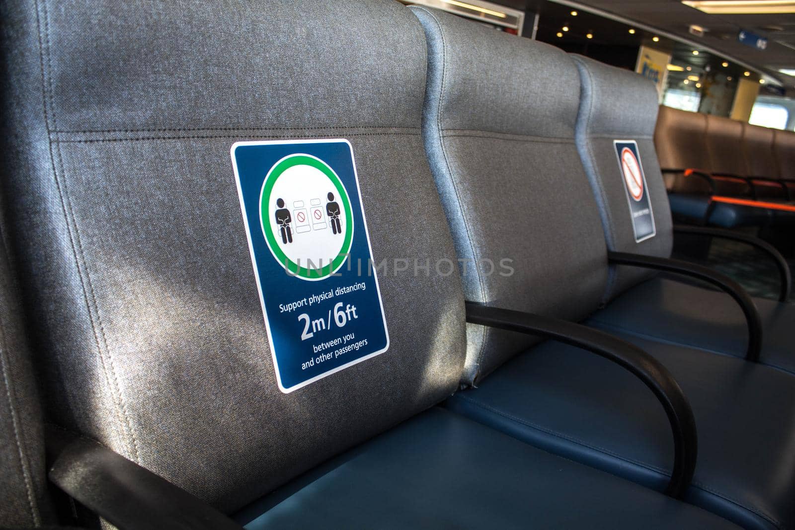 Perspective view of empty seats in the airport with social distancing regulation sign for COVID-19 epidemic awareness. Selective focus. by JuliaDorian