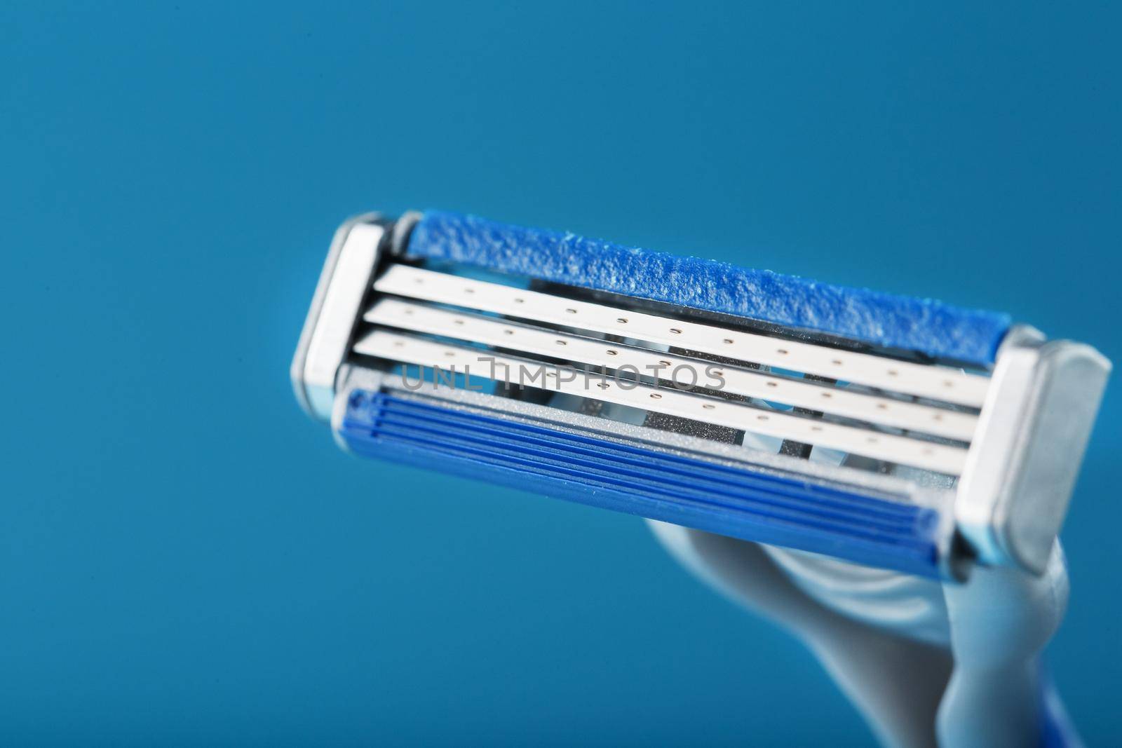 Shaving machine with three blades on a blue background close-up free space by AlexGrec