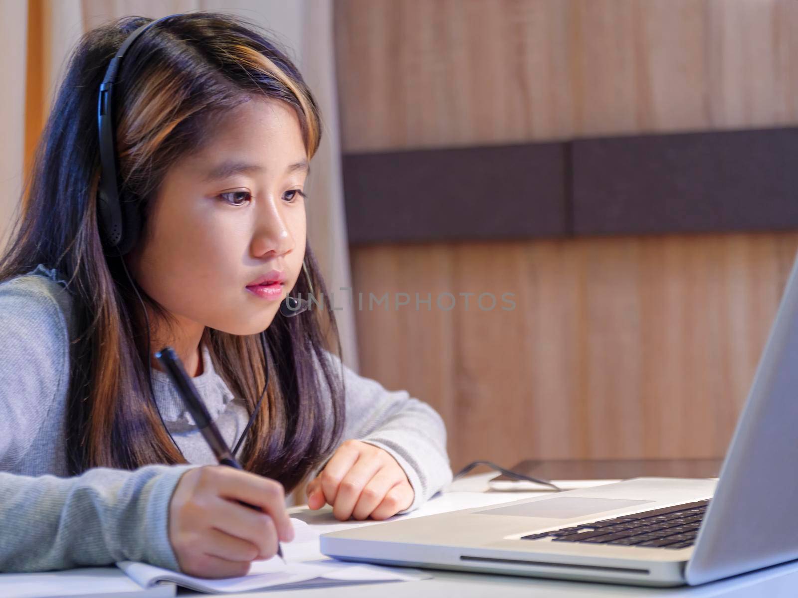 Asian girls study online with laptops. Kid wear headset typing keyboard notebook learning using internet lessons on quarantine. Students learn with internet online class from school Covid-19