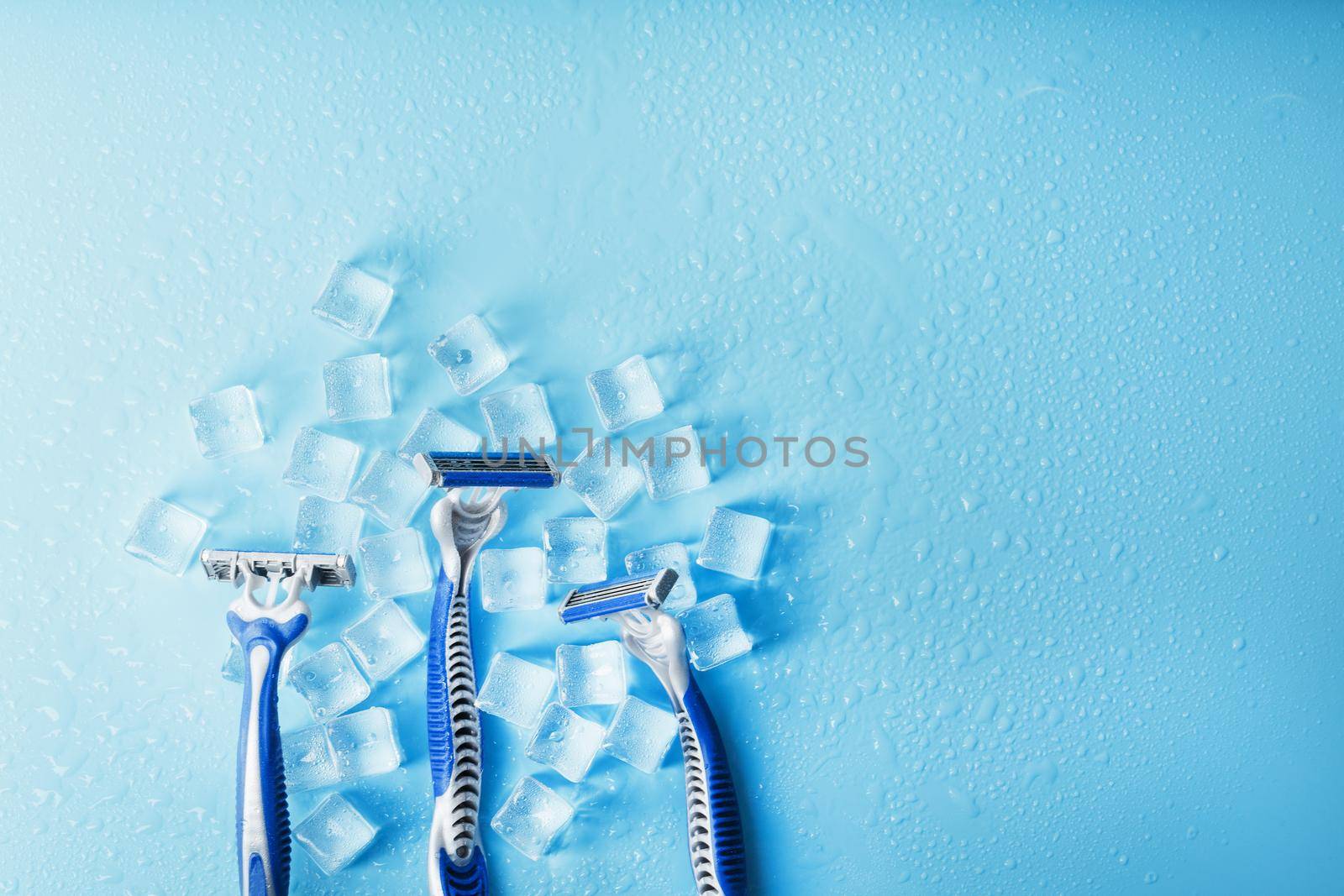 Shaving machine on a blue background with ice cubes. The concept of cleanliness and frosty freshness