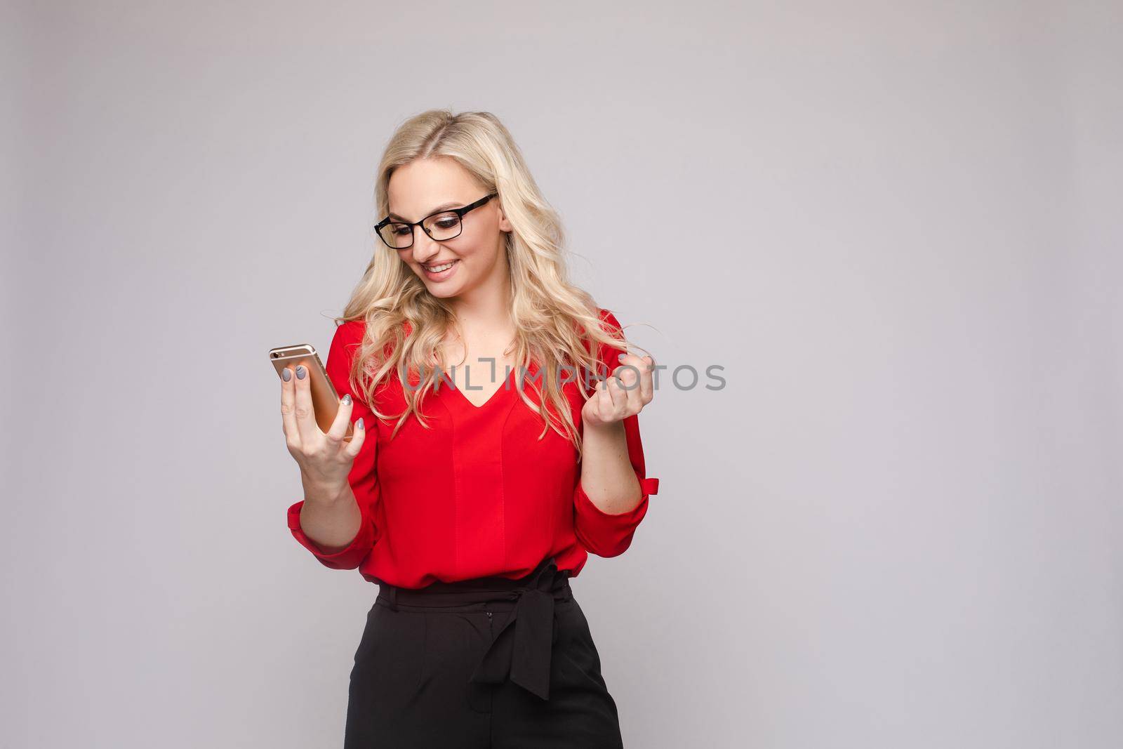Woman in red blouse and skirt keeping phone and laughing by StudioLucky