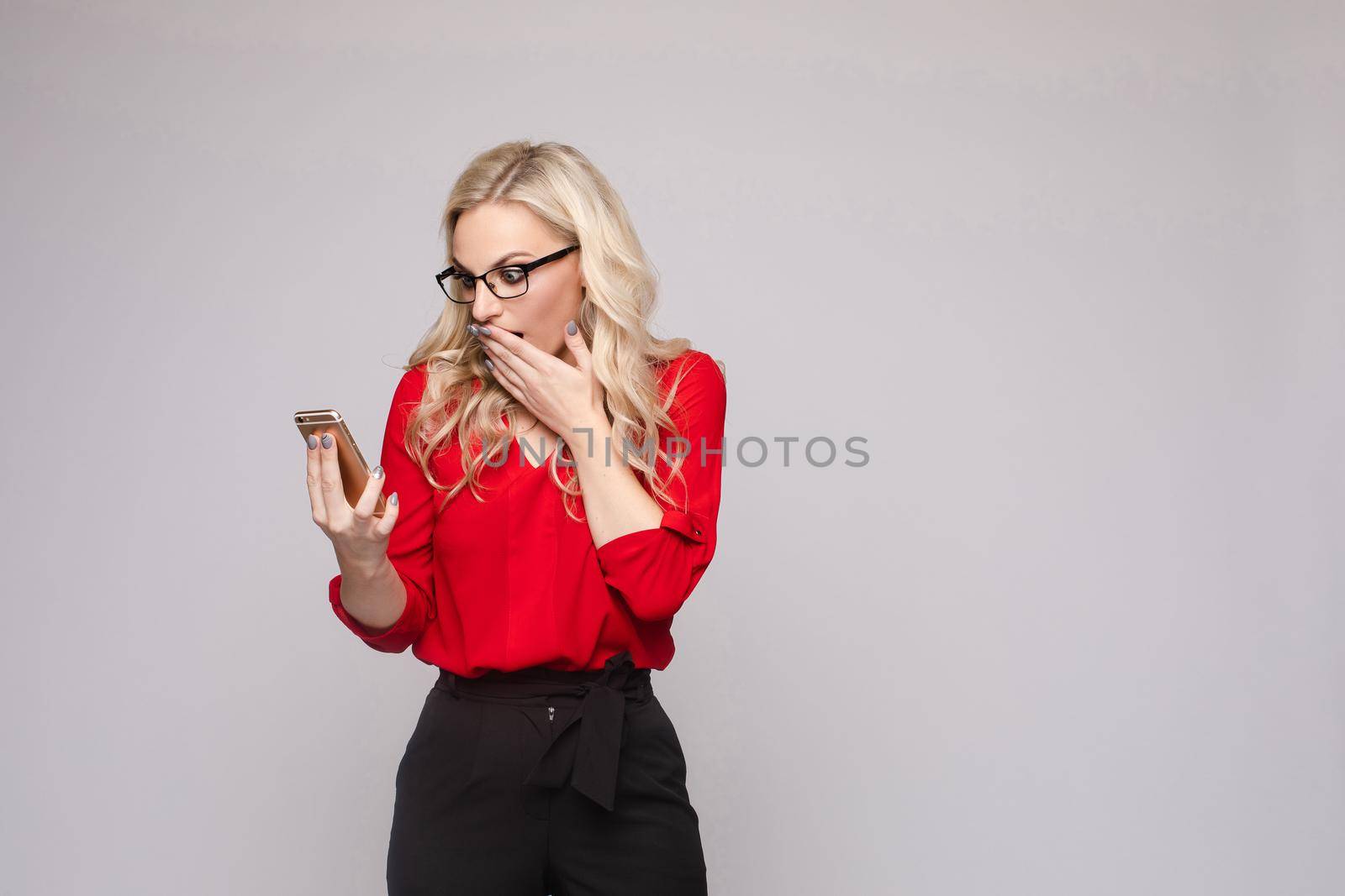 Woman in red blouse and skirt keeping phone and laughing by StudioLucky