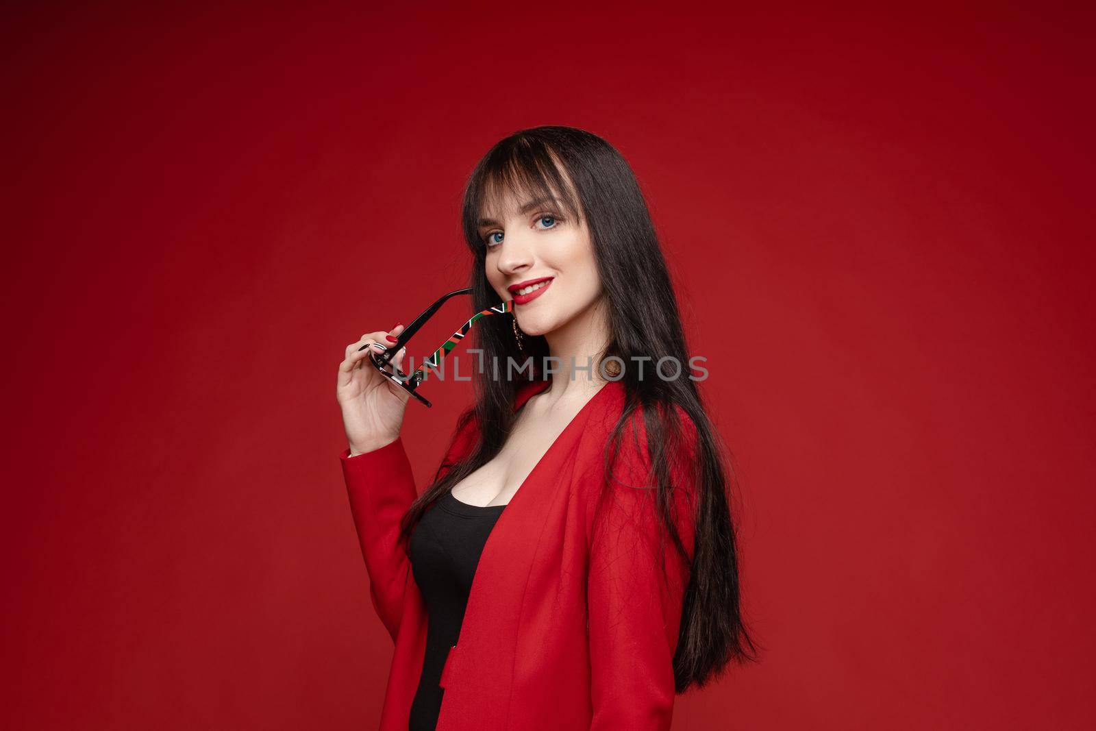 Side view of glamorous brunette posing in red smart suit by StudioLucky
