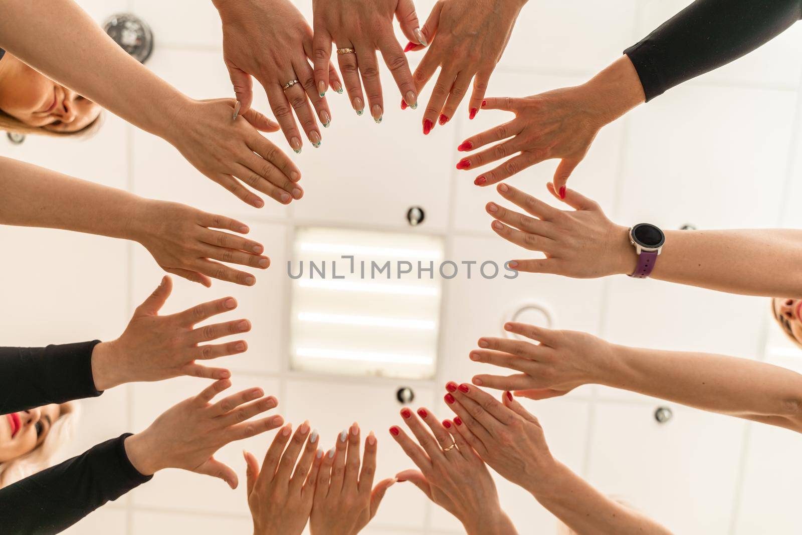 Team of people holding hands. Group of happy young women holding hands. Bottom view, low angle shot of human hands. Friendship and unity concept.