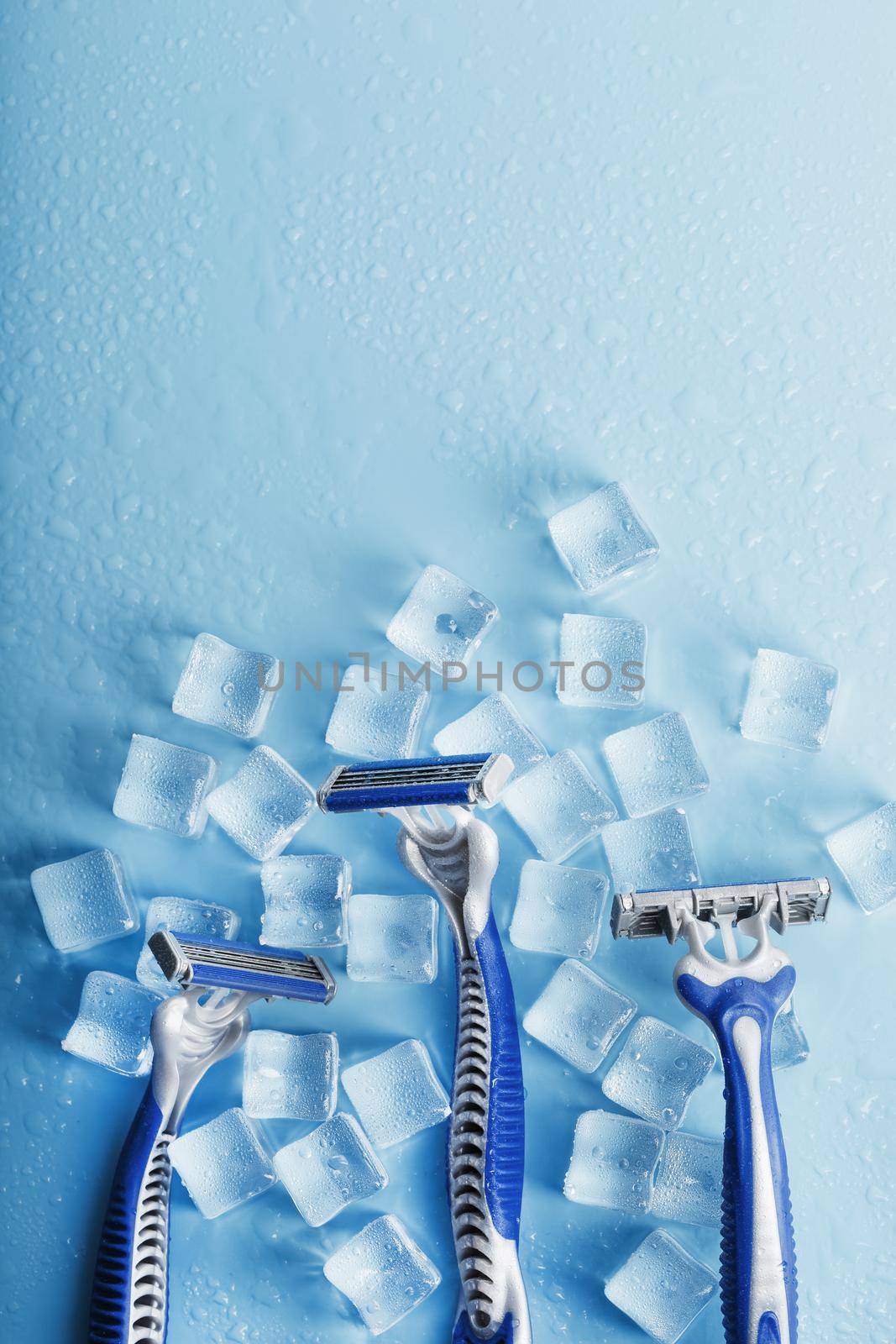 Shaving machine on a blue background with ice cubes. The concept of cleanliness and frosty freshness