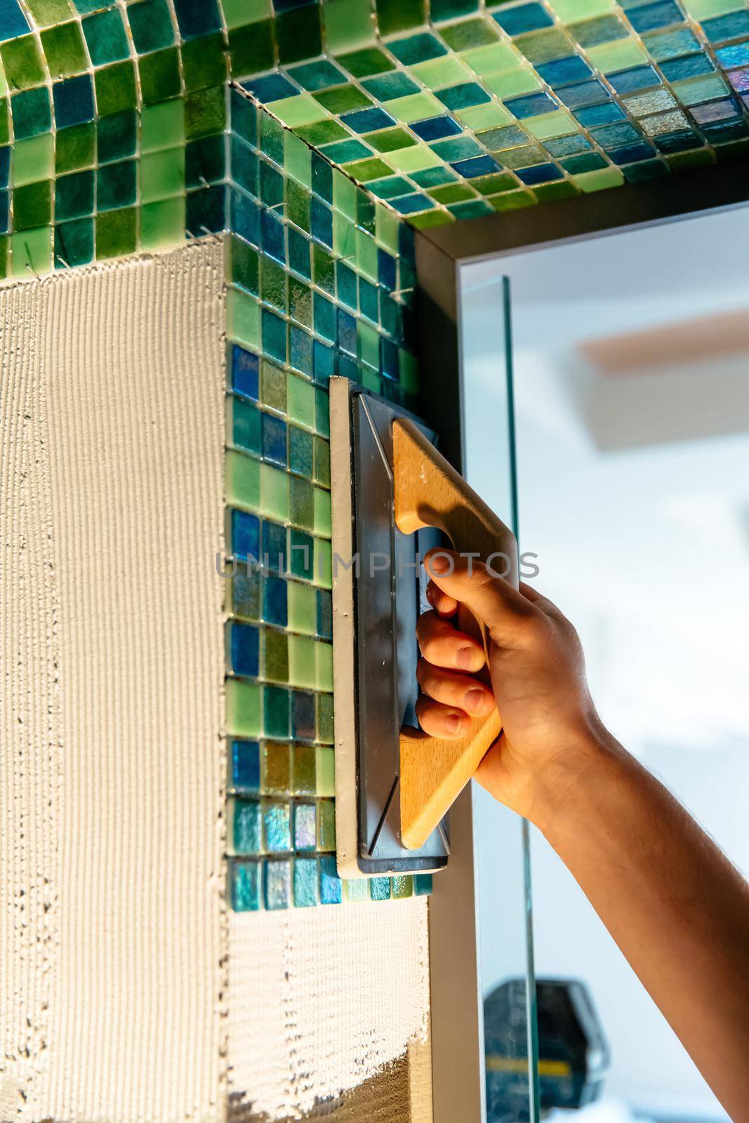 Applying mosaic tiles in bathroom, sauna walls. Construction tools and equipment. Spa or sauna relaxation modern room interior design. Adhesive for mosaic tile. Bath renovation.