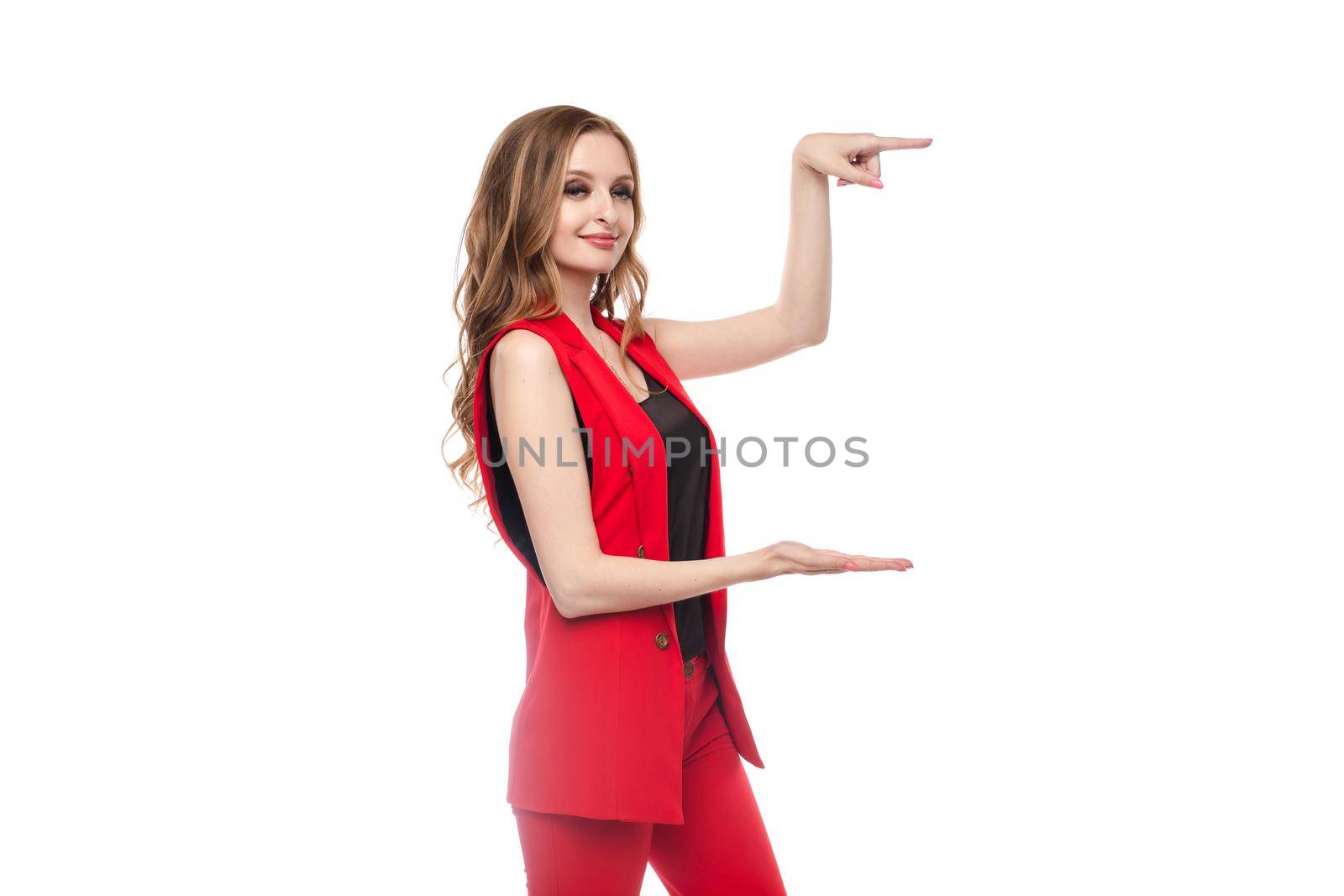 Side view of cheerful blonde in glasses, black skirt and red blouse looking at camera and gesturing with hands. Attractive woman keeping in hands copy space for text and object on isolated background.