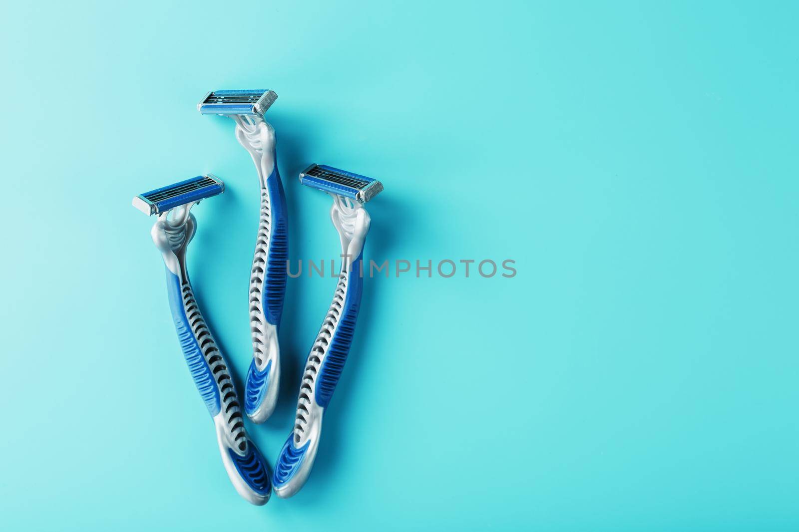 Blue shaving machine with sharp blades on the background of ice cubes close-up. The concept of cleanliness and frosty freshness