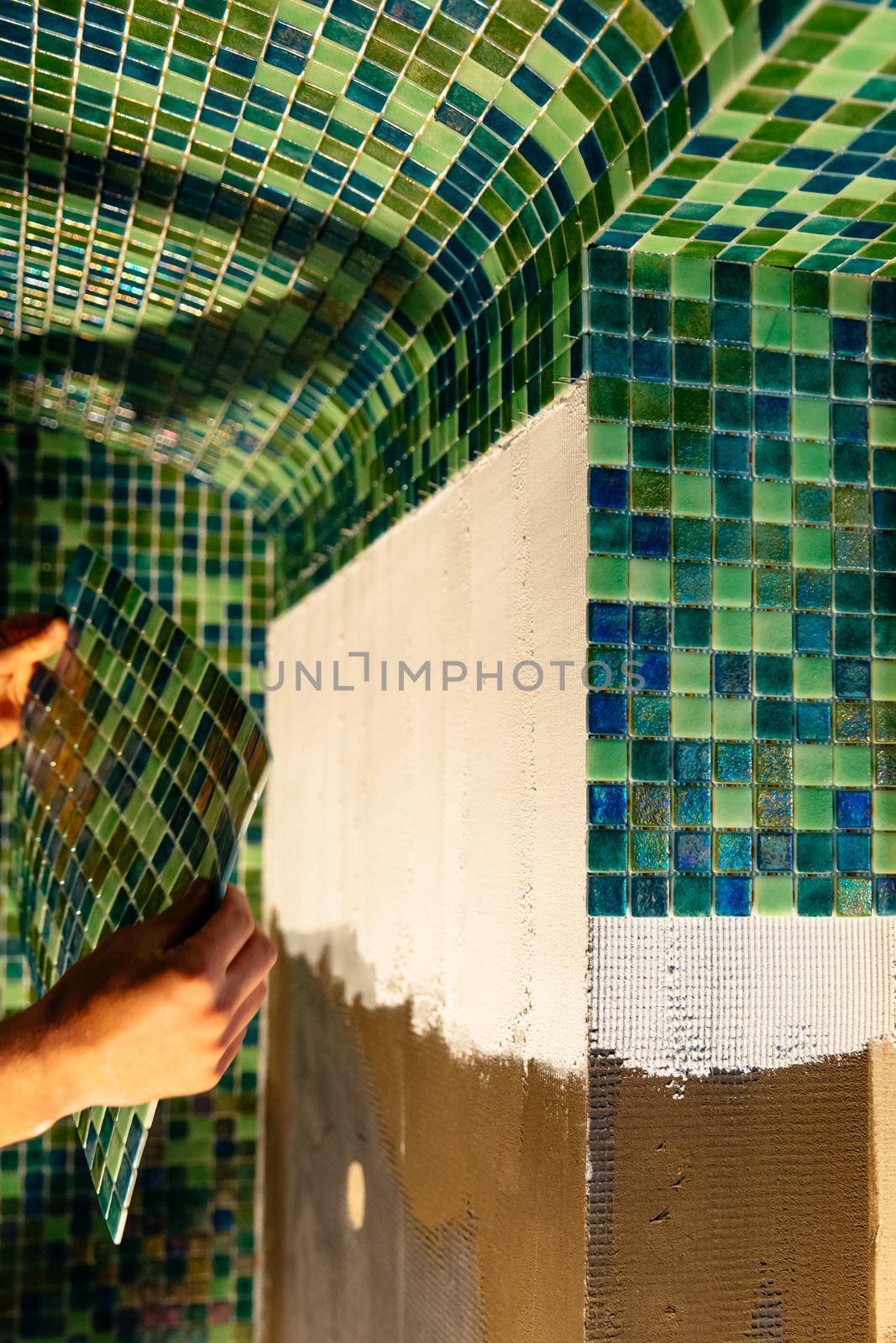 Green mosaic tiles on wall, small ceramic tiles. Sauna renovation concept