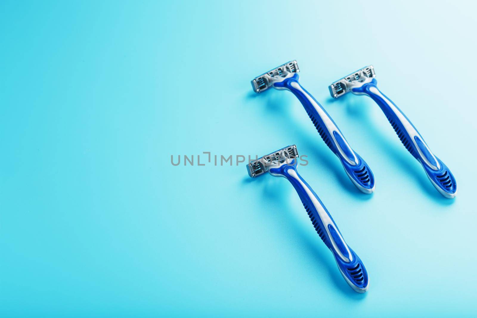 Blue shaving machine with sharp blades on the background of ice cubes close-up. The concept of cleanliness and frosty freshness