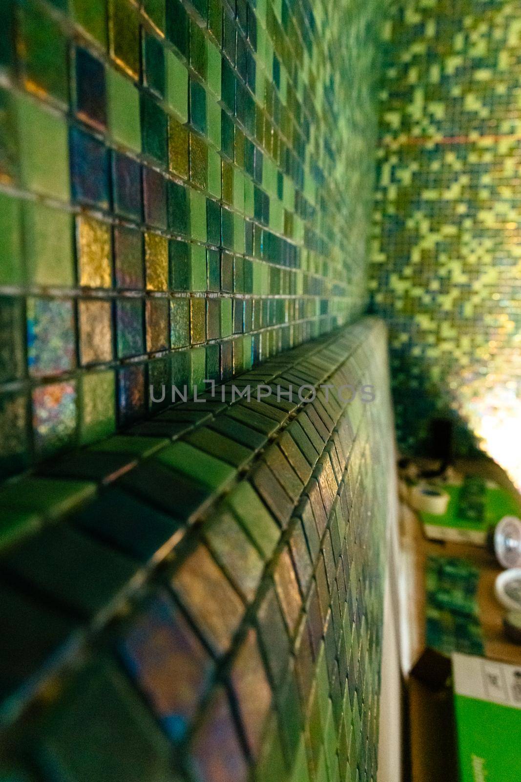 Close up modern green mosaic tiles on wall. Sauna room interior design with mosaic.