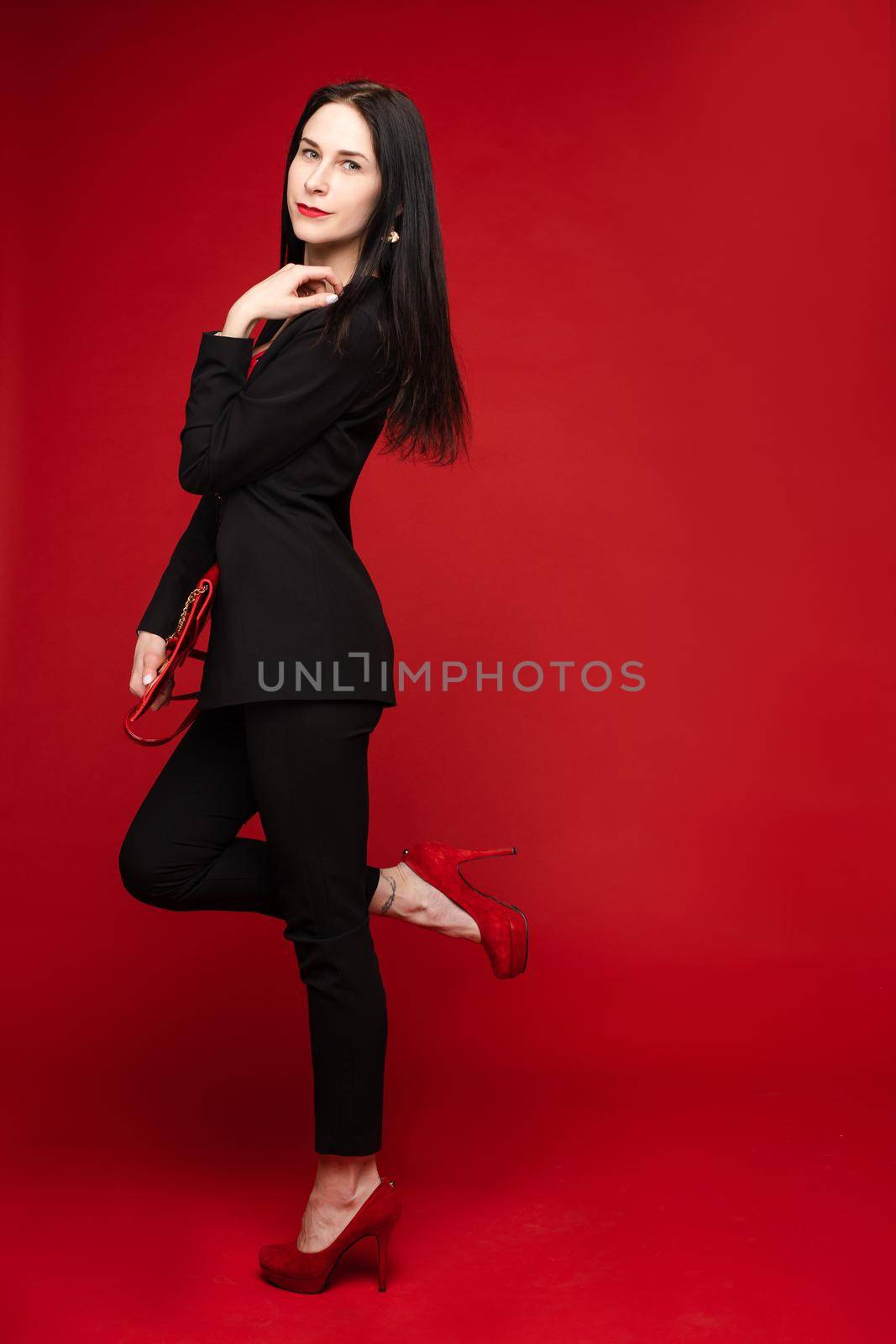 Portrait of young beautiful woman thoughtfully looking down. Brunette model in elegant costume posing at camera . Pretty lady in red sunglasses leaning one hand on other and holding it near face.