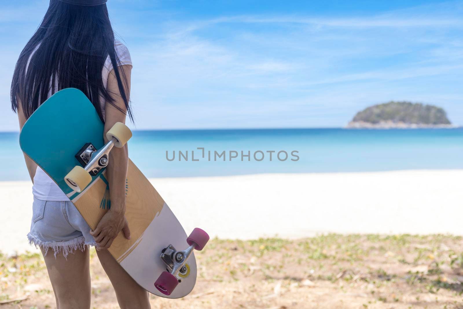 Young women hold surf skate board with beach background. Women stand with surf skate relax and enjoy with tropical beach with copy space