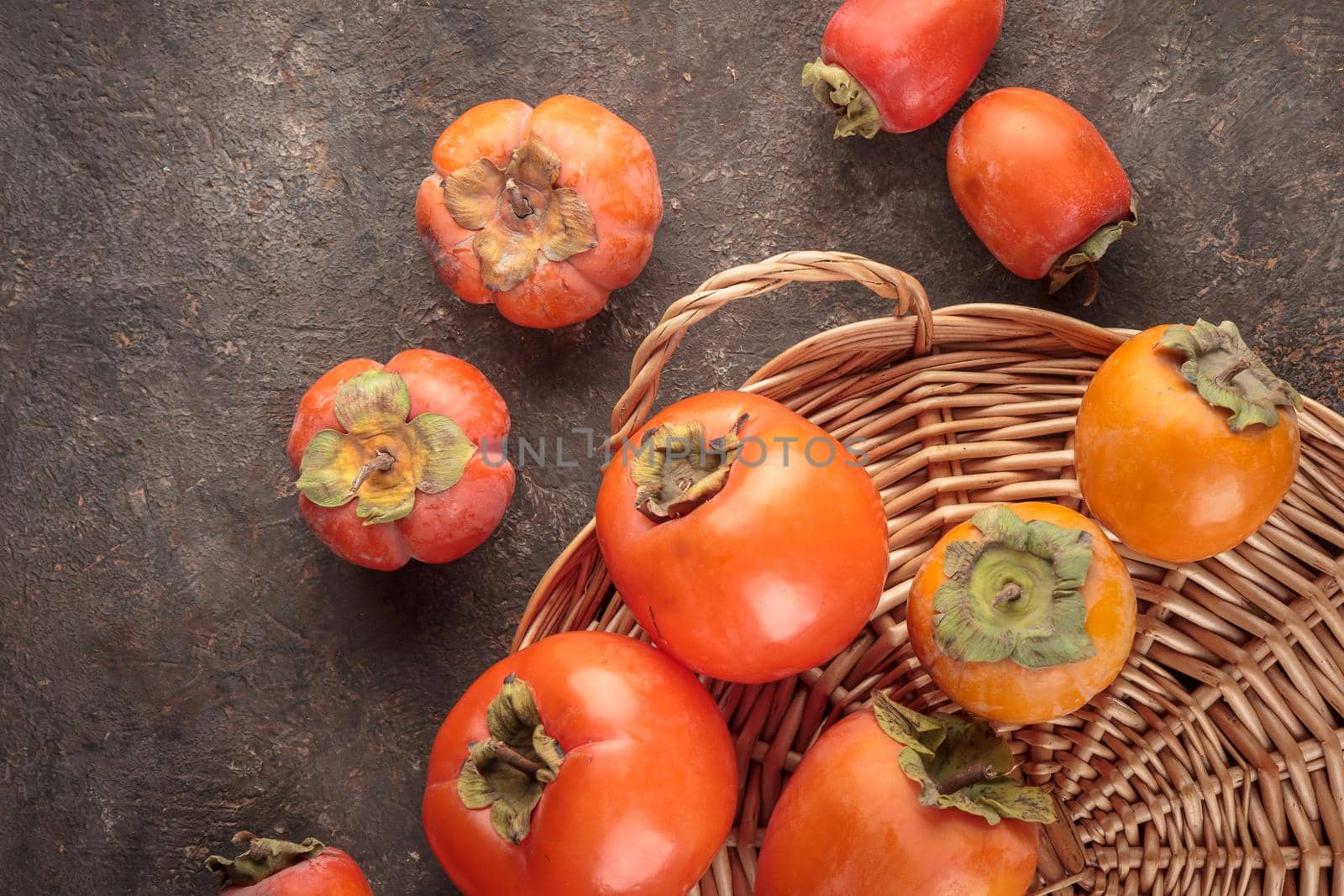 Different fresh persimmons on a dark background