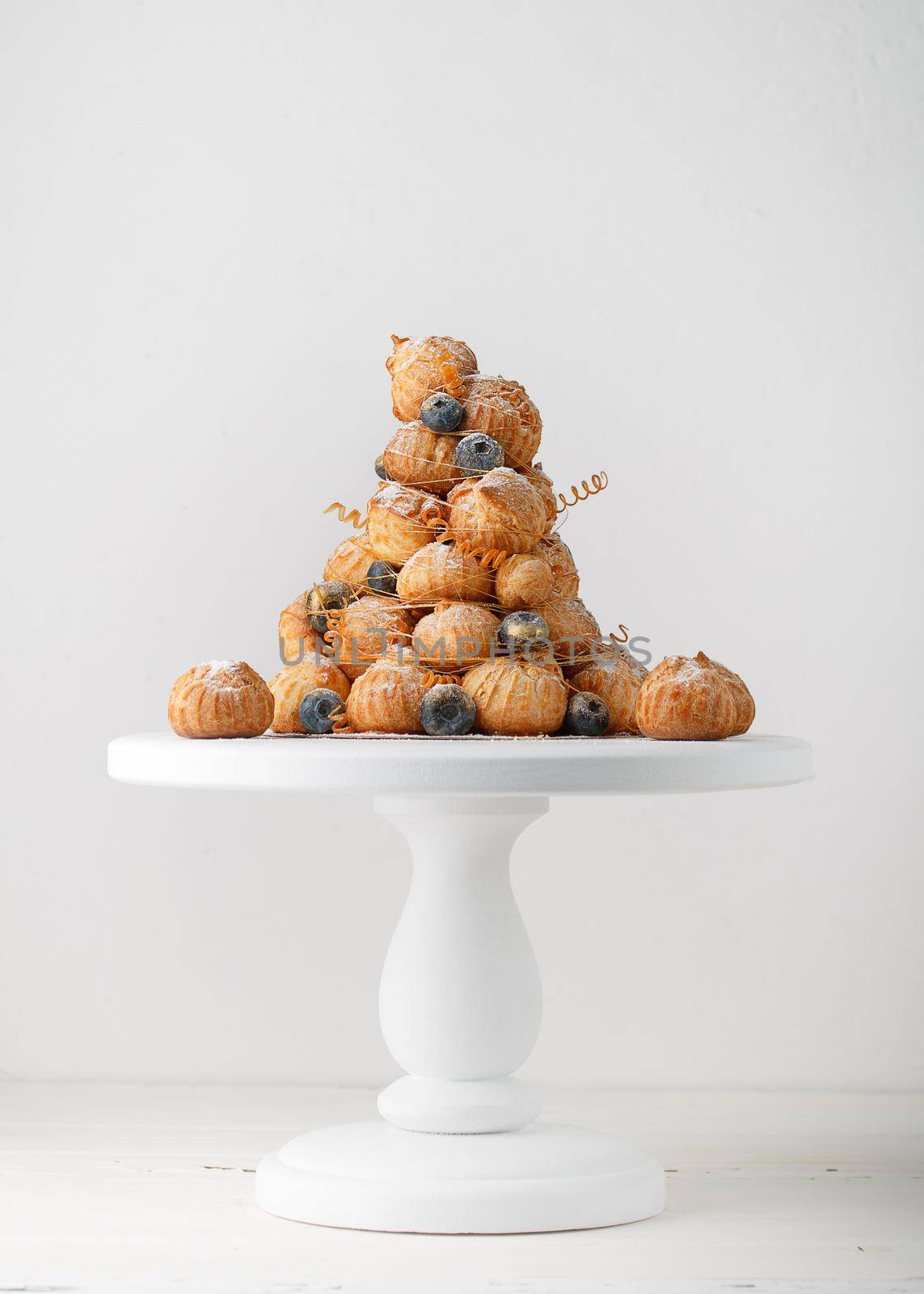 Crockembouche cake on a white stand and white background