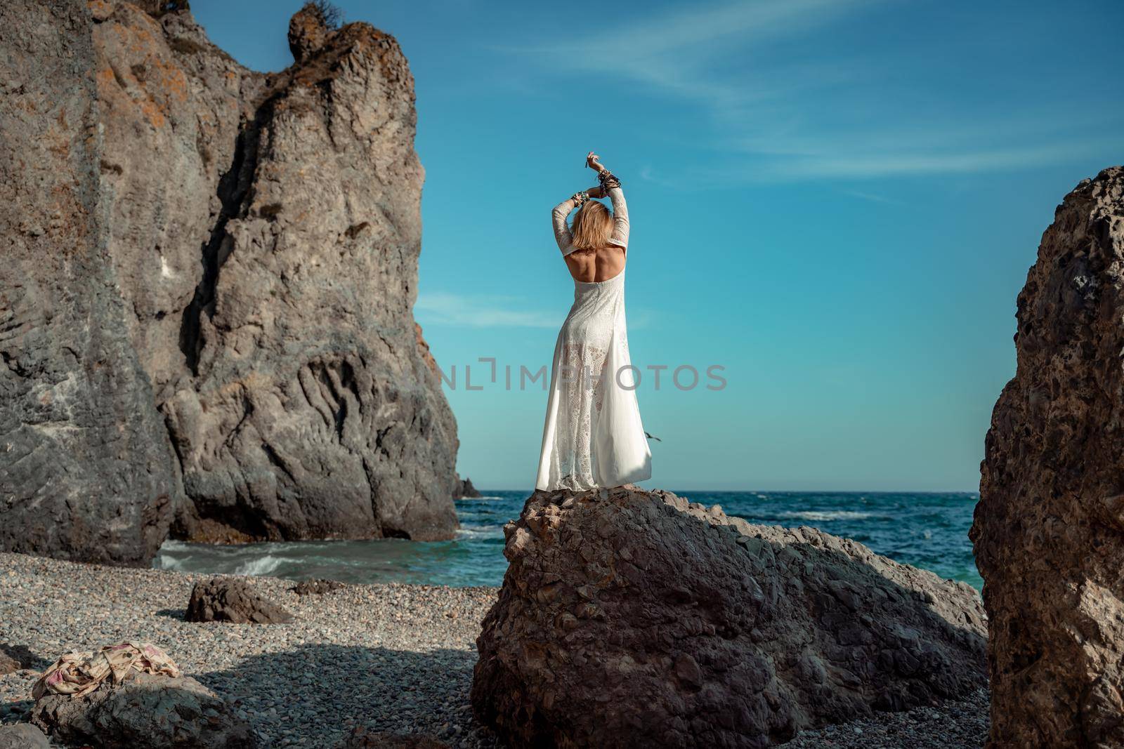 Middle aged woman looks good with blond hair, boho style in white long dress on the beach decorations on her neck and arms