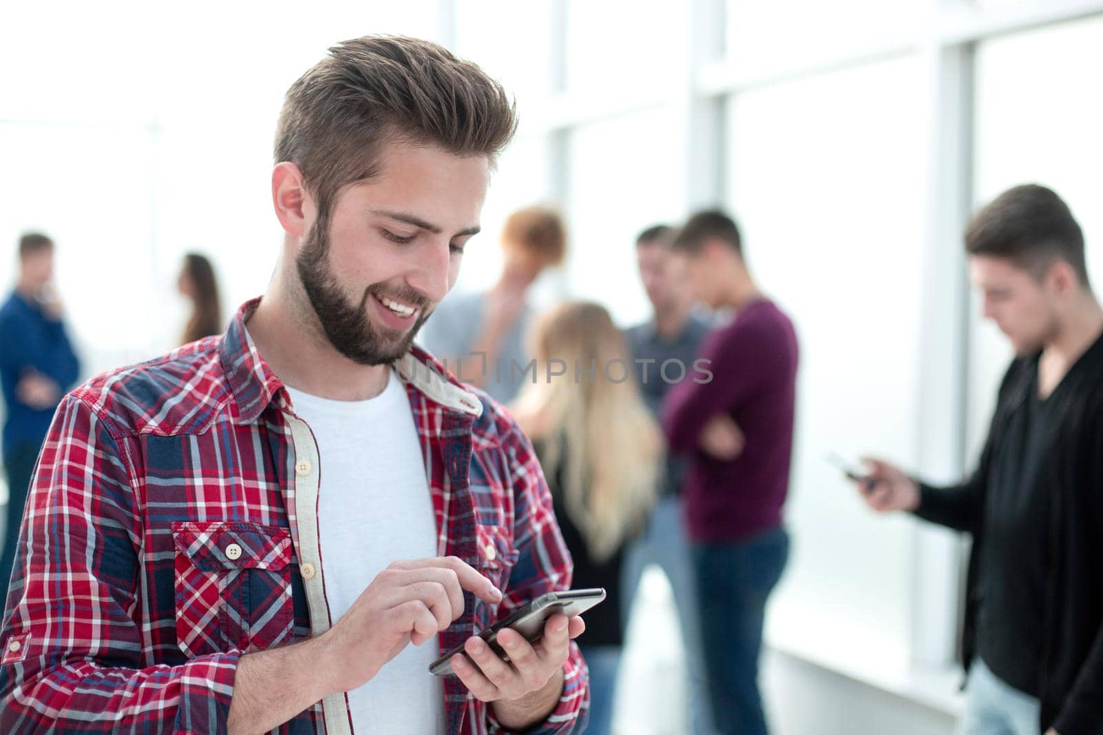 close up. smiling young designer reading a message on his smartphone