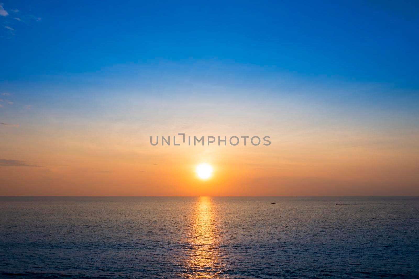 Beautiful sunset over the clam sea with cloud sky background. Sunset over tropical beach. Nature summer  concept. Peak sunset over sea with yellow light reflect on sea water. Tranquil seascape. Horizon over the water.