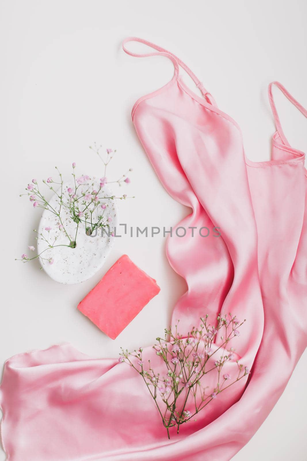 Spa composition with pink soap bar with ceramic soap dish, silk babric and flowers.