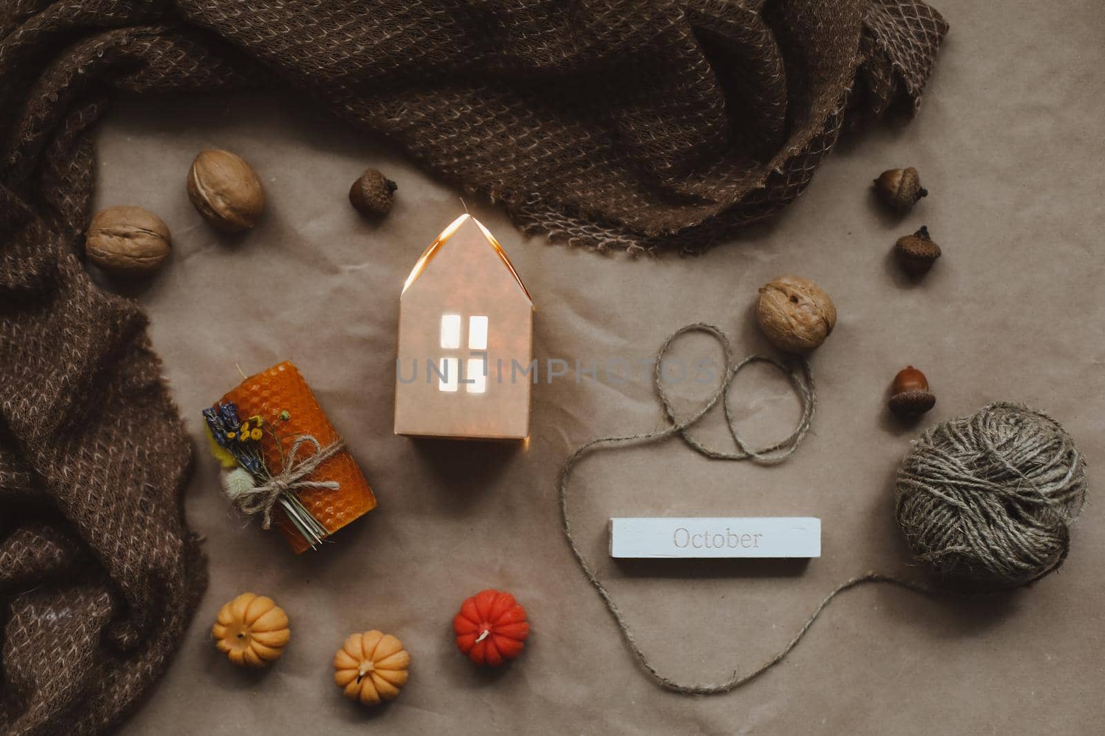 Cozy autumn composition with paper house surrounded by autumn leaves, candles and pumpkin top view. Hygge home decor. Halloween and Thanksgiving concept.